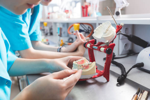 MEGATECH technician hand-finishing a dental prosthesis on an articulator